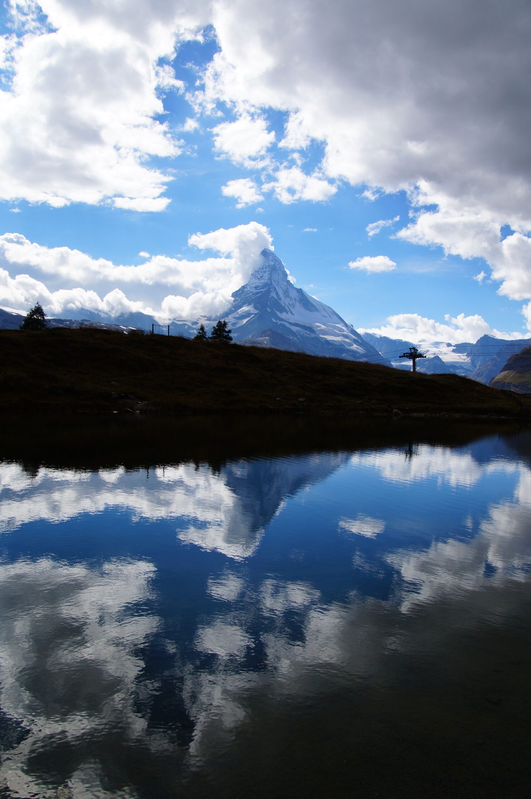 Majestic Matterhorn reflected in a serene lake under a cloudy sky.
